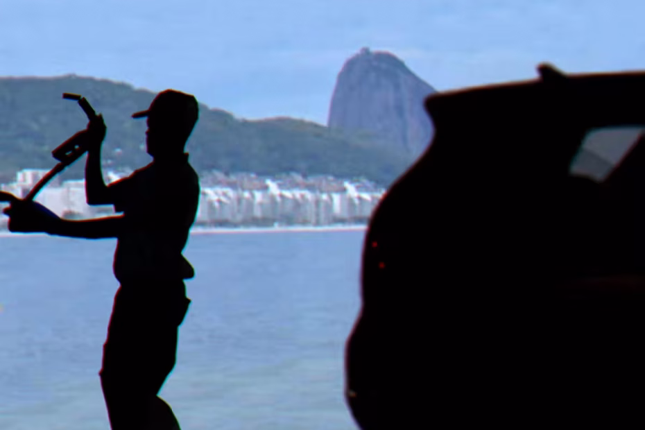 Um frentista de posto de gasolina abastece um veículo, com o Pão de Açúcar ao fundo, visto a partir da Praia de Copacabana, no Rio de Janeiro | Montagem